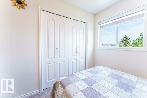 White bi-fold closet doors with panel detailing, light neutral wall paint, and a white-framed window with roller shades - 3525 22 Street, Edmonton, AB - Indoor Photo Showing Bedroom