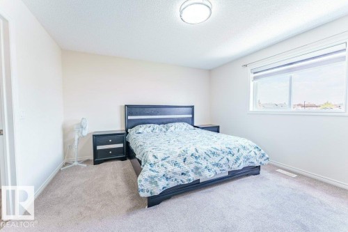 Spacious room featuring neutral carpeting, light-toned walls, and a large window with roller shades - 3525 22 Street, Edmonton, AB - Indoor Photo Showing Bedroom