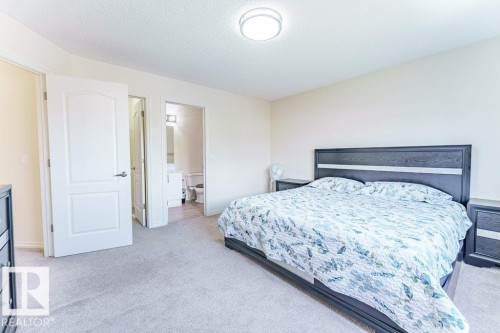 Carpeted room featuring a white interior door, a bathroom entrance with a vanity and toilet visible, and a ceiling-mounted light fixture - 3525 22 Street, Edmonton, AB - Indoor Photo Showing Bedroom