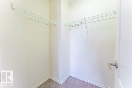 Walk-in closet featuring wire shelving, wall-mounted hooks, light-toned walls, and carpet flooring - 3525 22 Street, Edmonton, AB - Indoor With Storage