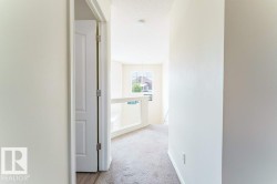 Upper-level hallway with neutral carpeting and light-toned wall finishes - 