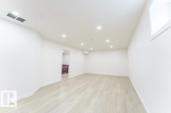 Spacious room featuring light wood-finish flooring, recessed lighting, and a white color palette - 