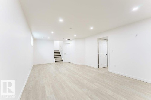 Spacious room featuring light wood-finish flooring, recessed lighting, and crisp white walls - 3525 22 Street, Edmonton, AB - Indoor