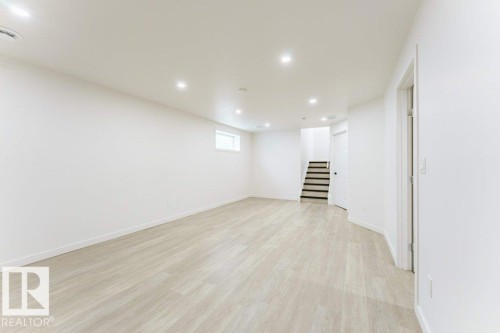 Spacious room featuring light wood-finish flooring, recessed lighting, white walls, and a window for natural illumination - 3525 22 Street, Edmonton, AB - Indoor