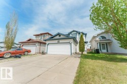 Siding exterior with a double garage, concrete driveway, and front lawn - 