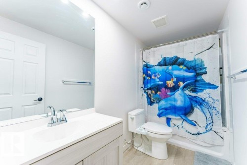 Bathroom featuring a single vanity with an integrated sink, chrome faucet, and light wood-finish cabinetry - 3525 22 Street, Edmonton, AB - Indoor Photo Showing Bathroom