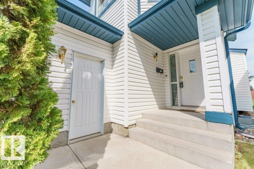 Front entry with white siding exterior and blue soffit, featuring a paneled entry door with decorative glass insert and a secondary utility door - 3525 22 Street, Edmonton, AB - Outdoor With Exterior
