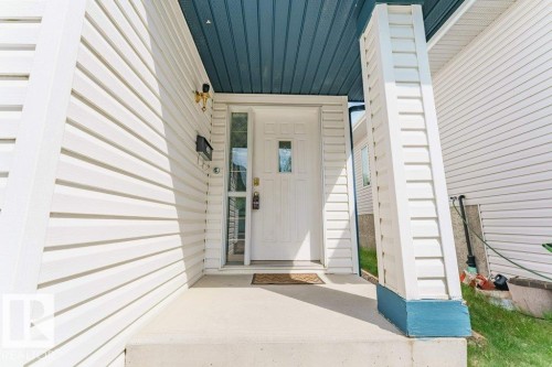 Front entry featuring a white paneled door with decorative glass, a sidelight, and a concrete porch - 3525 22 Street, Edmonton, AB - Outdoor With Exterior