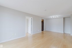 Spacious room with light wood-finish flooring, light gray walls, and white baseboards - 
