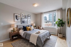 Bedroom featuring wood-finish flooring and a large window with city architecture visible - 