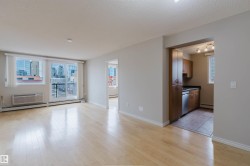 Open-concept living space with light wood-finish flooring, white baseboards, and neutral wall paint - 