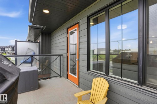 Concrete balcony featuring glass and black metal railings, a privacy screen, and a dark wood-finish soffit - 58 Jensen Gate, St. Albert, AB 