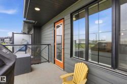 Concrete balcony featuring glass and black metal railings, a privacy screen, and a dark wood-finish soffit - 