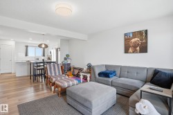 Open-concept living area featuring wood-finish flooring, white walls, and a recessed ceiling light - 