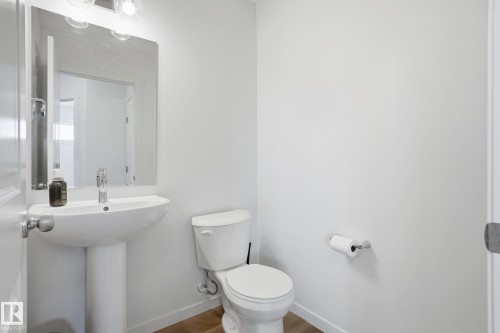 Contemporary pedestal sink with a chrome faucet, illuminated by a modern vanity light fixture - 58 Jensen Gate, St. Albert, AB 