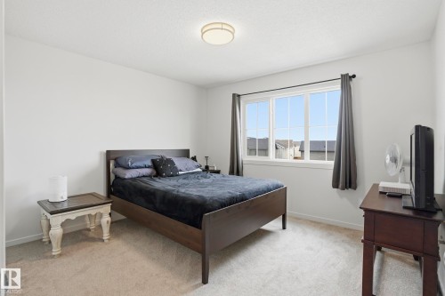 Carpeted bedroom featuring white walls and a large window with white framing - 58 Jensen Gate, St. Albert, AB 
