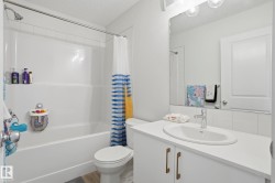 Full bathroom featuring a white tub with shower, white tile surround, and a vanity with a drop-in sink - 