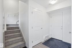 Entryway featuring light wood-finish flooring, a carpeted staircase with white railings, and multiple white panel doors - 
