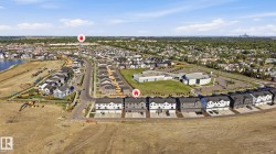 Aerial perspective of a developing residential community featuring a variety of housing types, including row houses and detached homes - 