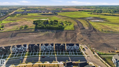 New construction residential development featuring a row of multi-story homes with contrasting dark and light facades - 58 Jensen Gate, St. Albert, AB 