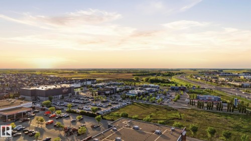Aerial perspective showcasing commercial establishments, residential housing, and surrounding green spaces - 58 Jensen Gate, St. Albert, AB 