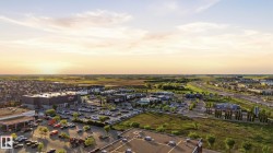 Aerial perspective showcasing commercial establishments, residential housing, and surrounding green spaces - 