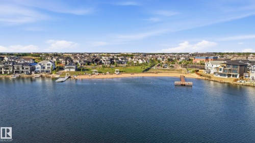 Expansive waterfront community featuring a private sandy beach, multiple docks, residential properties, and clear blue water - 58 Jensen Gate, St. Albert, AB 