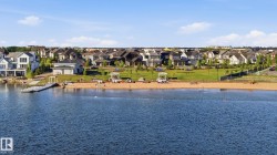 Expansive waterfront community featuring a sandy beach, floating dock, and grassy recreational areas - 
