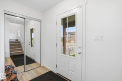 Entryway featuring wood-finish flooring, a white paneled door with glass inserts, and a sliding mirrored closet door - 