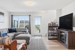Living area featuring light wood-finish flooring, white walls, and recessed lighting - 
