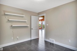 Neutral-toned room featuring dark gray tile flooring and white baseboards - 