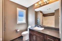 Bathroom featuring a dark wood-finish vanity with a dark countertop, white vessel sink, and chrome faucet - 