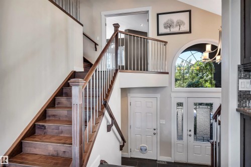 Two-story foyer featuring a grand staircase with dark wood-finish treads and white balusters - 9 Shorewood Crescent, Leduc, AB - Indoor Photo Showing Other Room