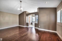 Expansive room featuring wood-finish flooring, vaulted ceilings, and a contemporary chandelier - 