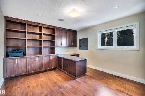 Room featuring extensive built-in cabinetry and shelving, wood-finish flooring, recessed lighting, and a large window - 9 Shorewood Crescent, Leduc, AB - Indoor Photo Showing Office