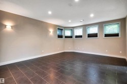 Spacious room featuring dark tile flooring, recessed ceiling lighting, and multiple windows with roller shades - 