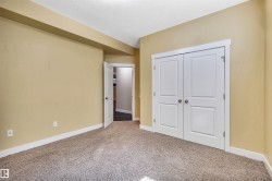 Room featuring neutral carpeting, light beige walls, white trim, and white paneled doors - 