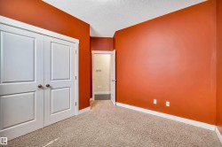 Warm-toned room featuring a textured ceiling, a carpeted floor, and white baseboards - 
