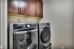 Laundry area featuring dark wood-finish cabinetry, light-toned walls, and a dedicated electrical outlet - 