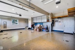 Spacious garage featuring epoxy flooring, built-in cabinetry, a utility sink area, and a window for natural light - 