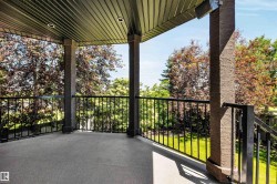 Covered patio featuring a textured floor, black metal railings, recessed lighting, and support columns with a textured finish - 