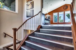 Grand staircase featuring dark tile treads with light risers, wood handrails, and metal balusters - 