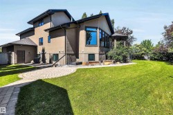 Expansive rear yard featuring a manicured lawn and a curved paver patio - 