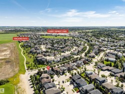 Aerial perspective of a residential community featuring extensive green spaces, a marked walking path, and mature trees - 