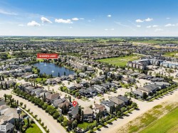 Aerial perspective showcasing a residential area featuring a central lake with fountains, surrounded by detached homes and mature trees - 