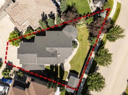 Expansive residential property featuring a large dwelling with a dark shingled roof, extensive green lawn areas, mature trees, and a paved driveway - 