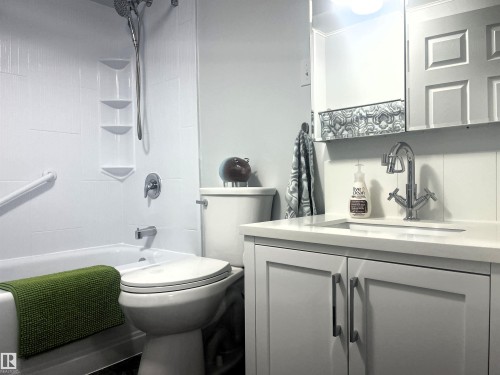 Bathroom featuring a white bathtub, shower with built-in shelving, chrome fixtures, and a grab bar - 4812 47 St, Drayton Valley, AB 