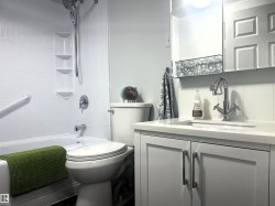Bathroom featuring a white bathtub, shower with built-in shelving, chrome fixtures, and a grab bar - 