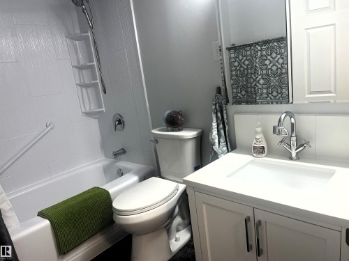 Modern bathroom featuring a white vanity with integrated sink, chrome faucet, and panel-style cabinetry - 4812 47 St, Drayton Valley, AB 