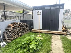 Modern storage shed with a sloped roof design, transom windows, and double doors, set on a raised wood platform - 